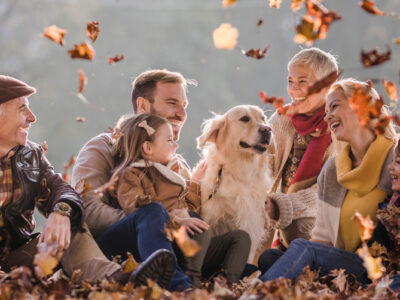 Happy multi-generation family and their dog relaxing in autumn leaves at the park.