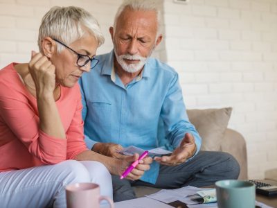 Senior couple having a hard time at home, calculating incoming bills and debt.